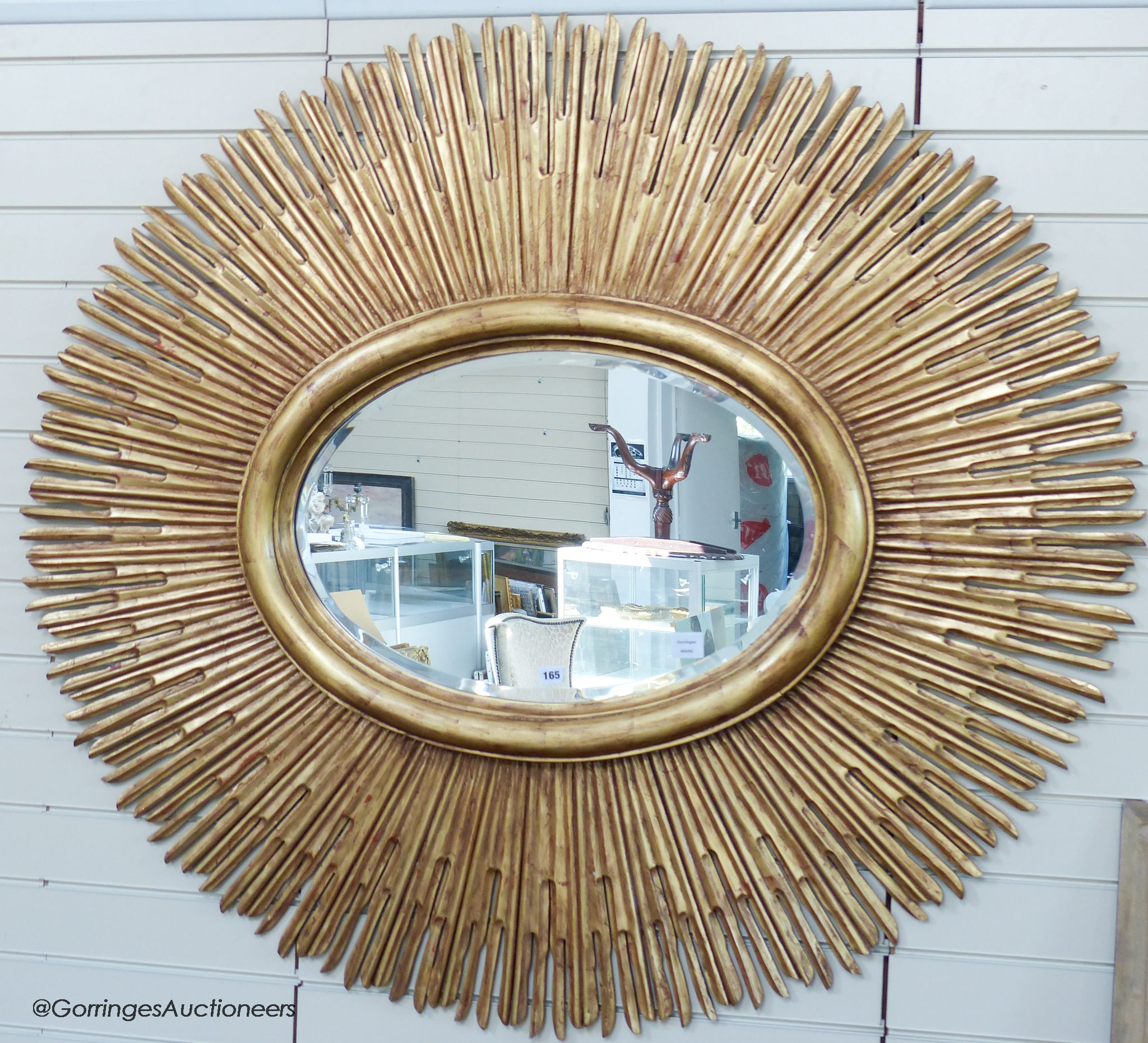 A large contemporary gilt oval 'sunburst' mirror, 145 cm wide, 130 cm high